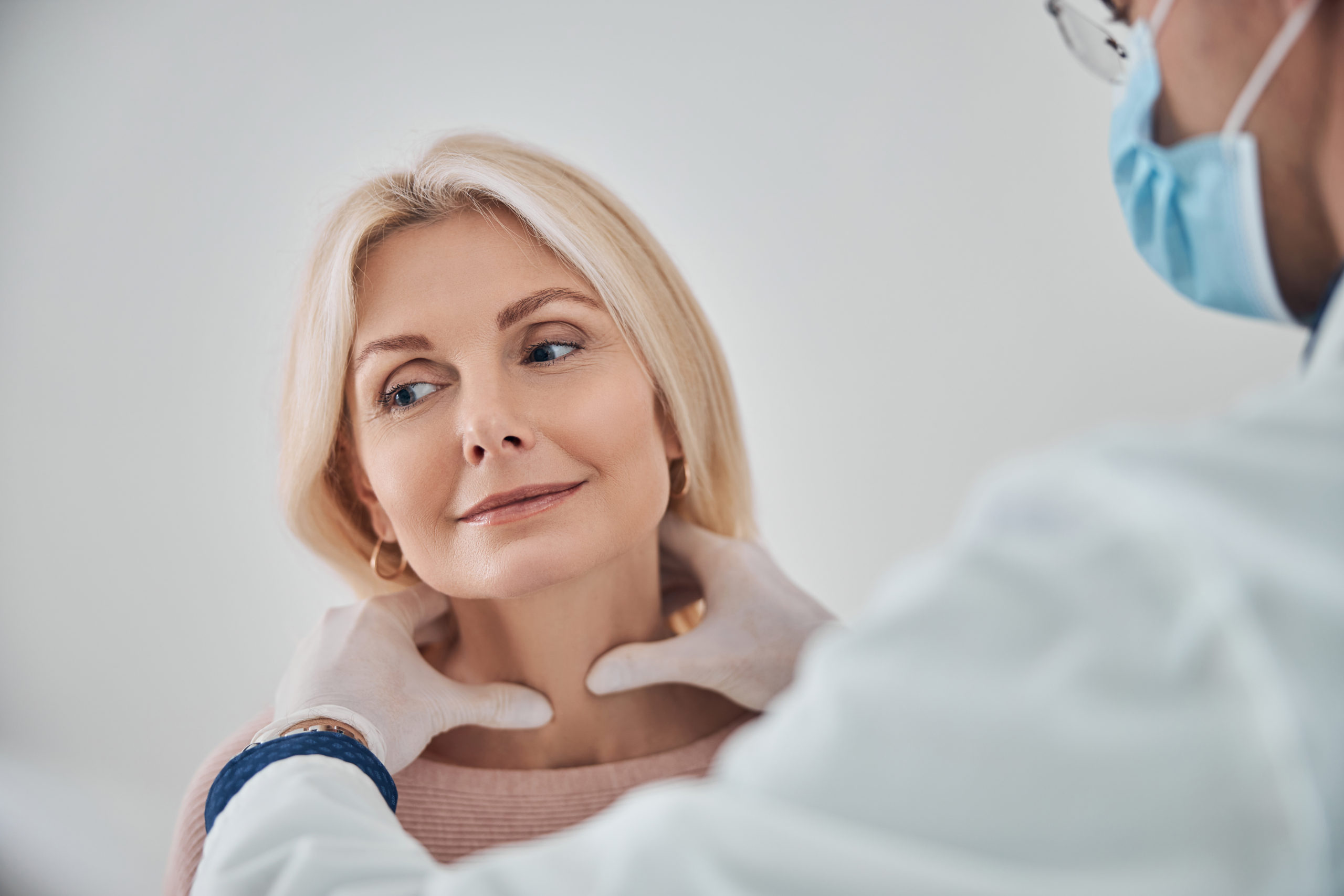 A woman having her thyroid checked by a doctor