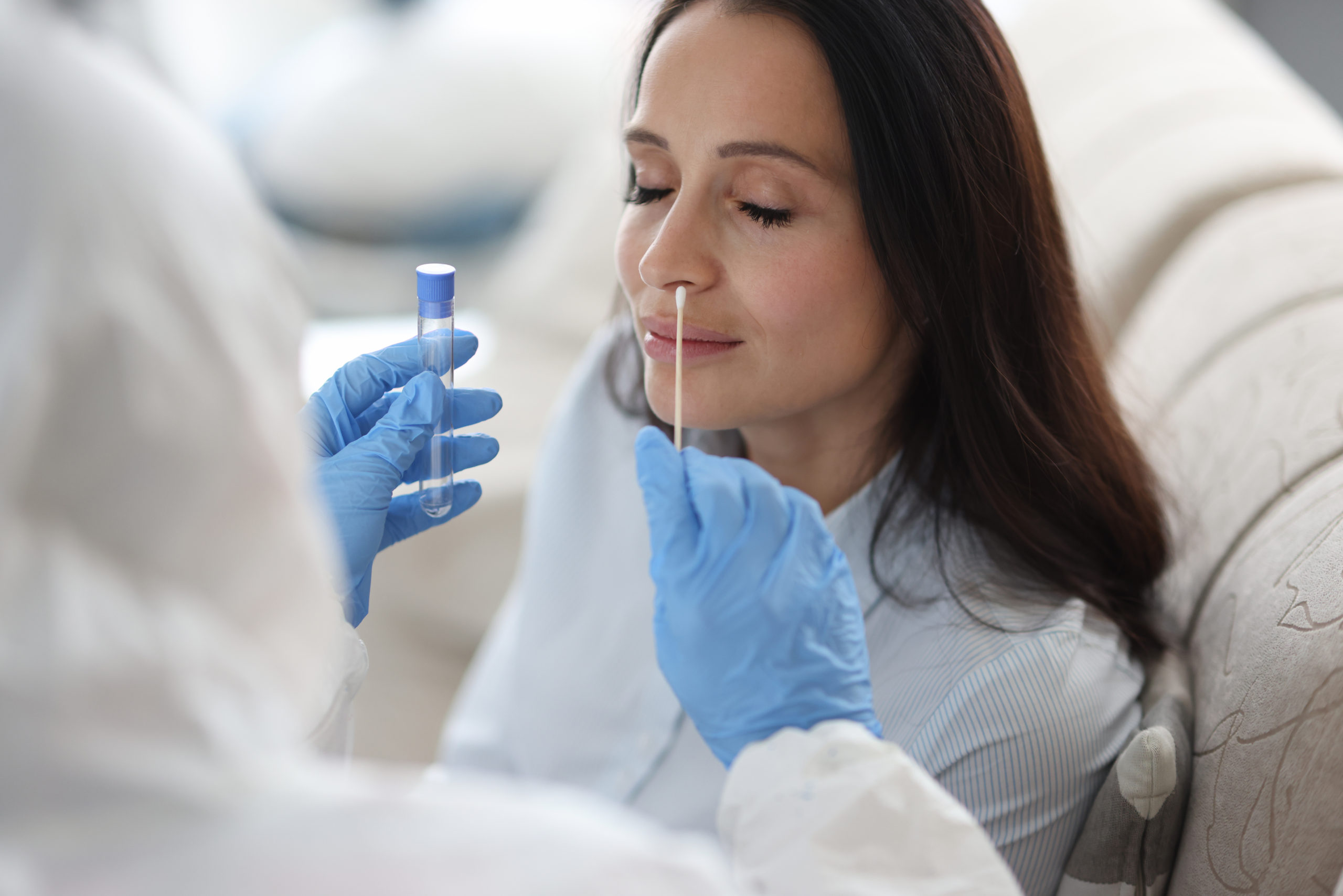 Woman getting a covid test from a doctor in a protective suit